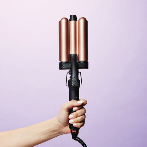 hand-holding-interchangeable-curler-base-with-waver-attached-purple-background